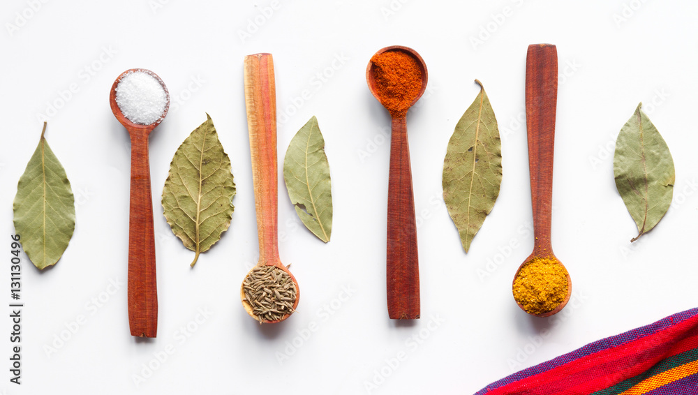 spices in wooden spoons on white background top view