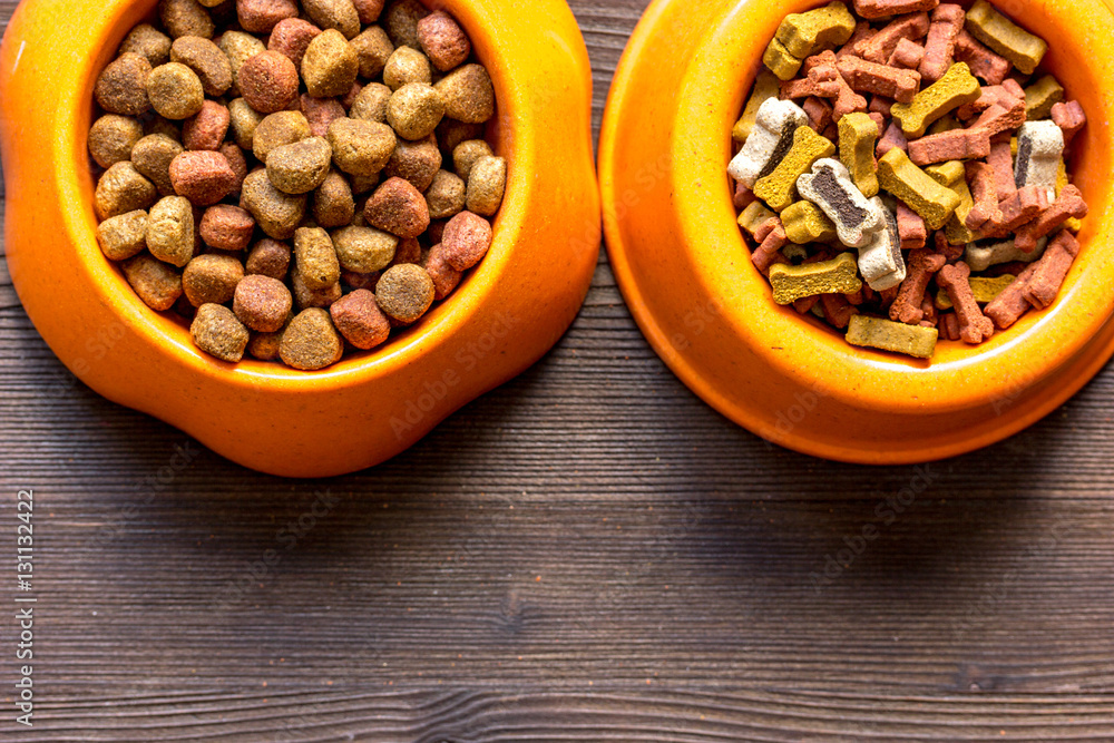 dry dog food in bowl on wooden background top view