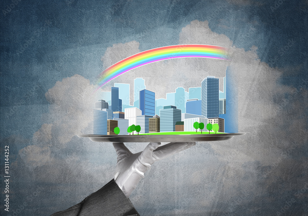 Hand holding metal tray with modern city model against concrete background