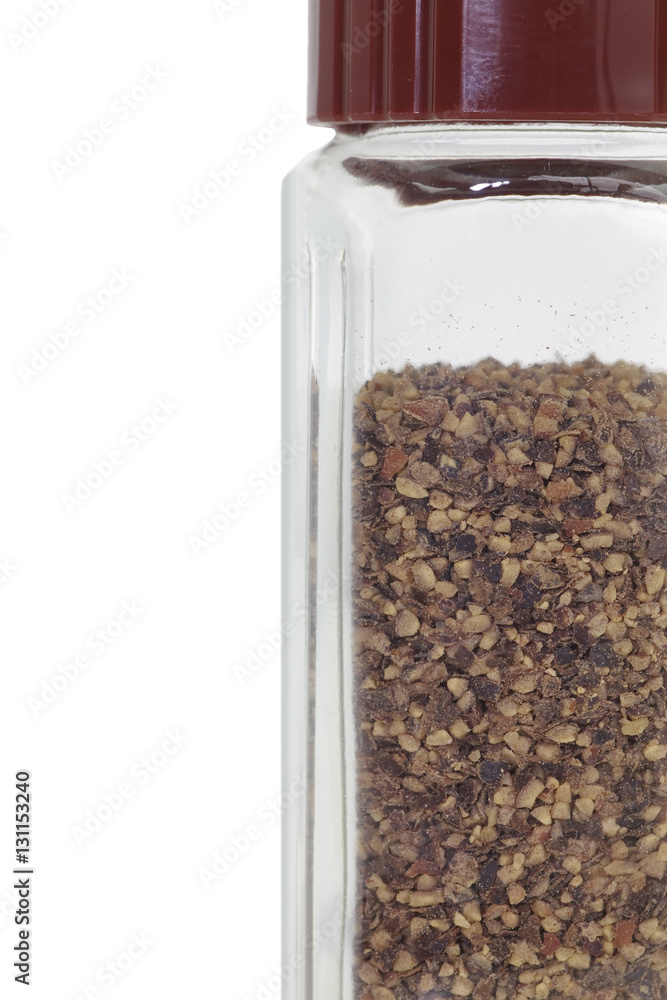 Glass bottle of black pepper isolated on a white background..