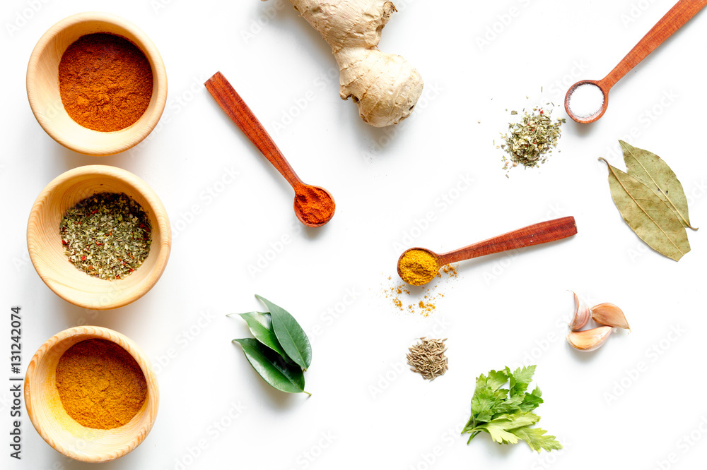 spices in wooden spoons on white background top view