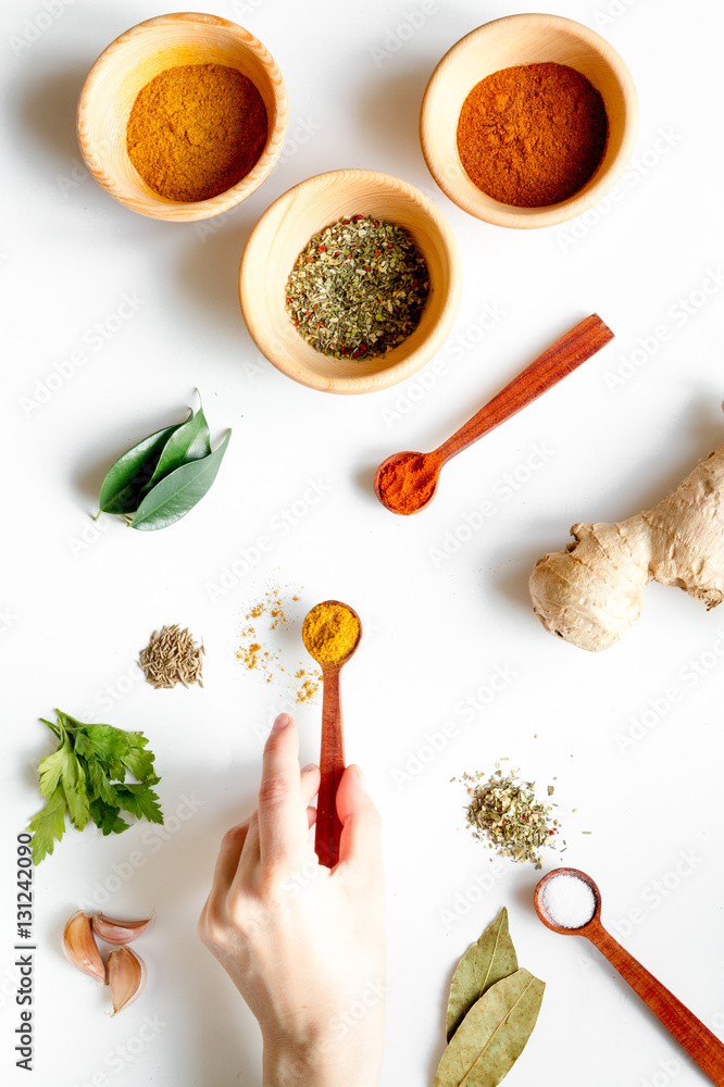 spices in wooden spoons on white background top view