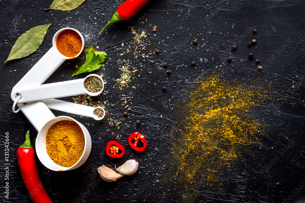 spices in wooden spoons on dark background top view