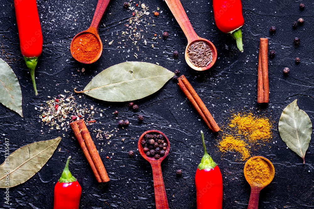 spices in wooden spoons on dark background top view