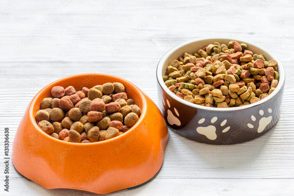 dry dog food in bowl on wooden background