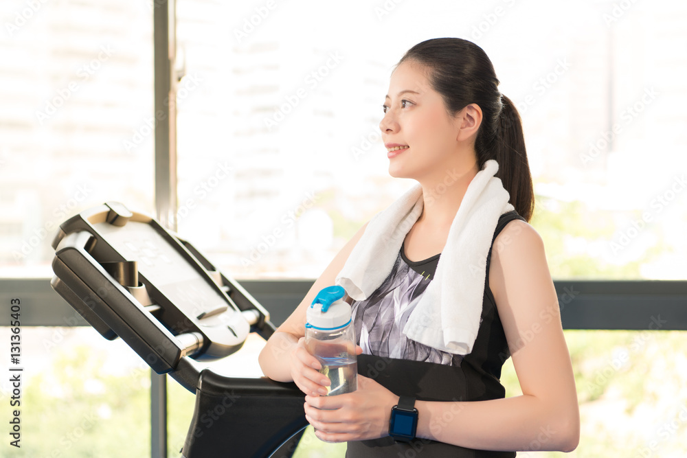 Beautiful asian woman rest holding water bottle after treadmill