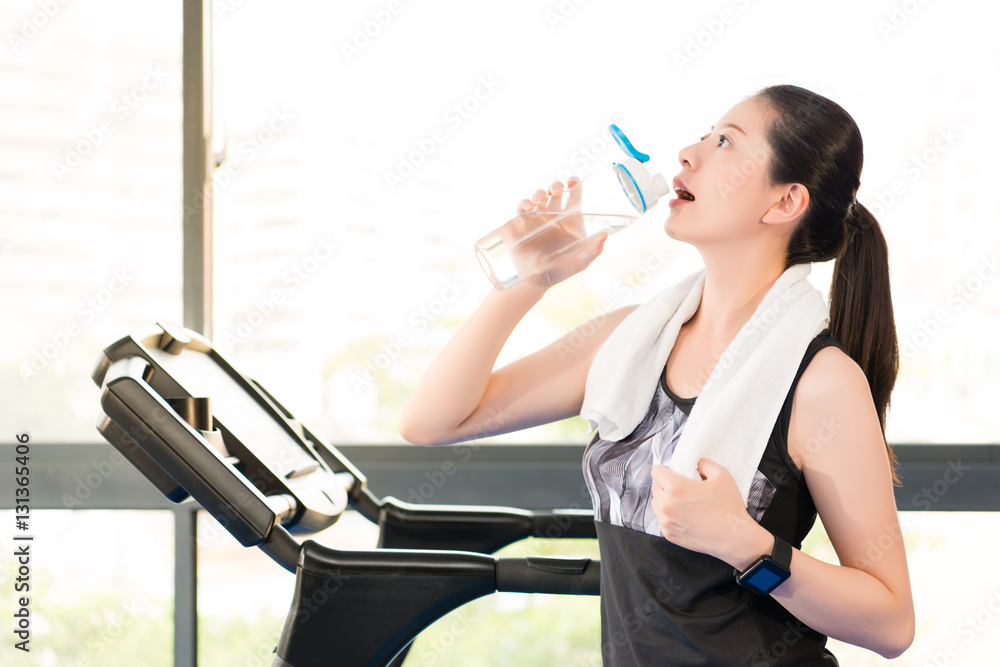 Beautiful asian woman rest drinking water bottle after treadmill