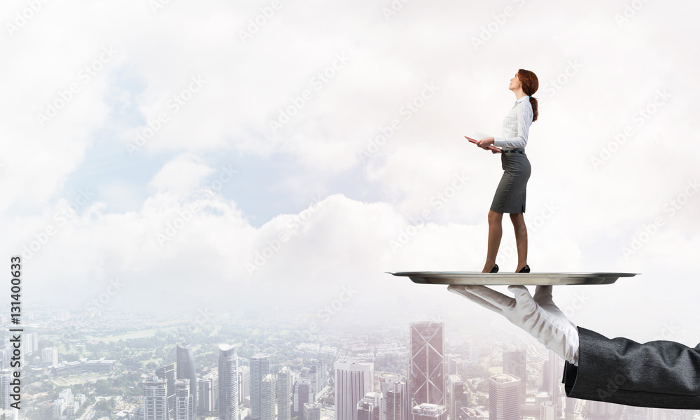 Attractive businesswoman on metal tray with red book in hands against cityscape background