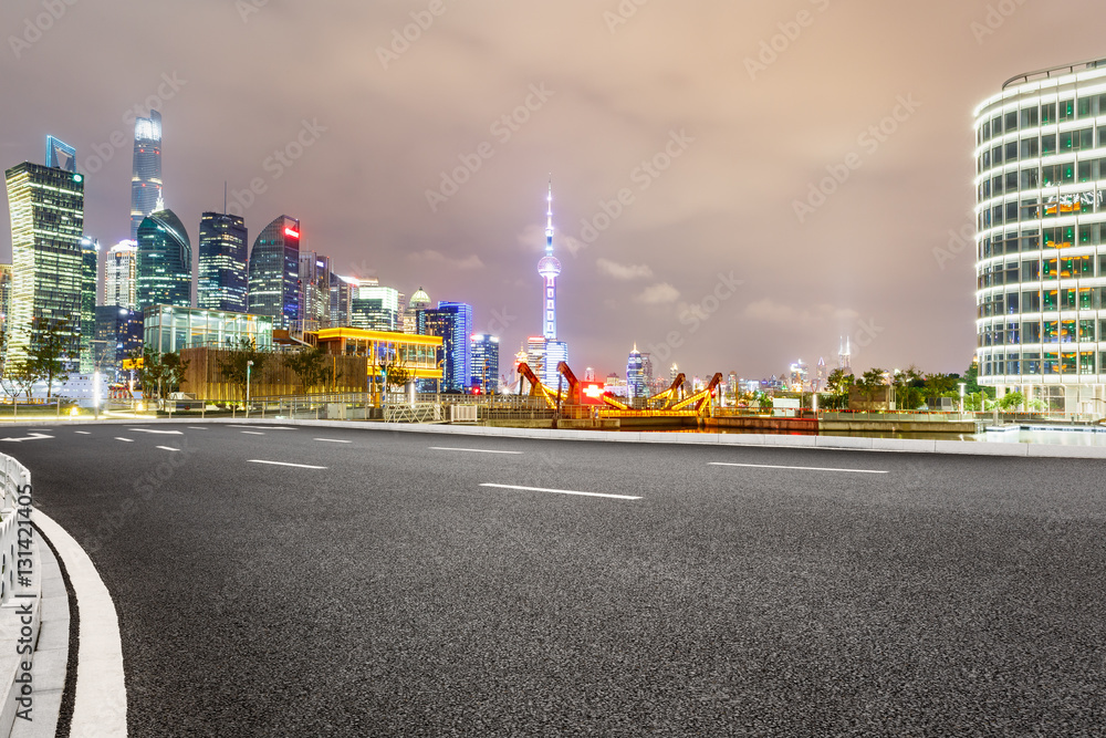 Asphalt road and modern cityscape at night in Shanghai