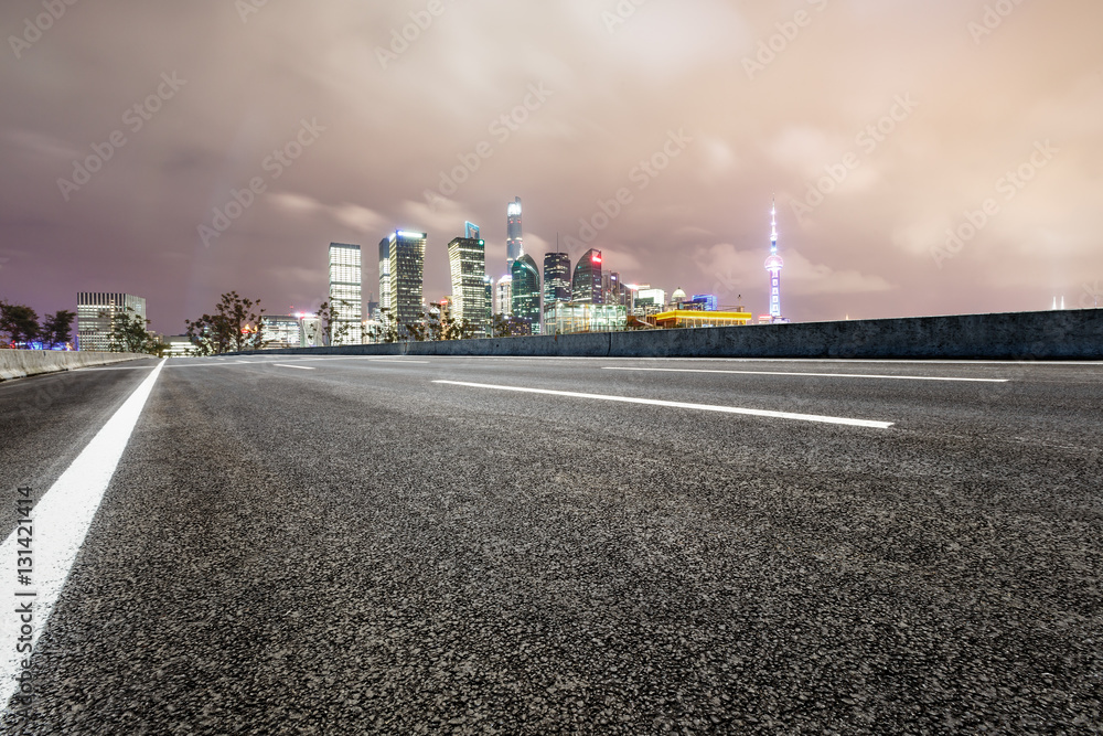 Asphalt road and modern cityscape at night in Shanghai