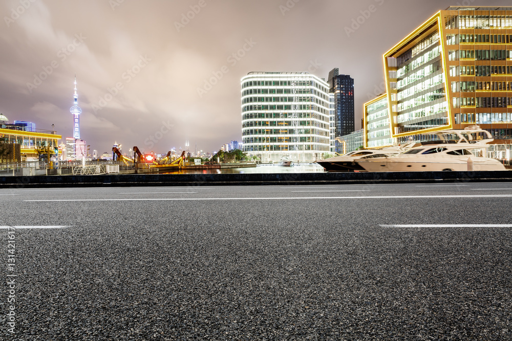 Asphalt road and modern cityscape at night in Shanghai