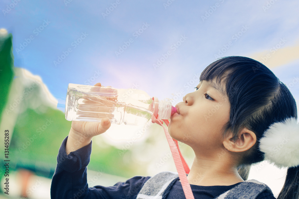 学校的孩子们在背景天空下用瓶子喝水。