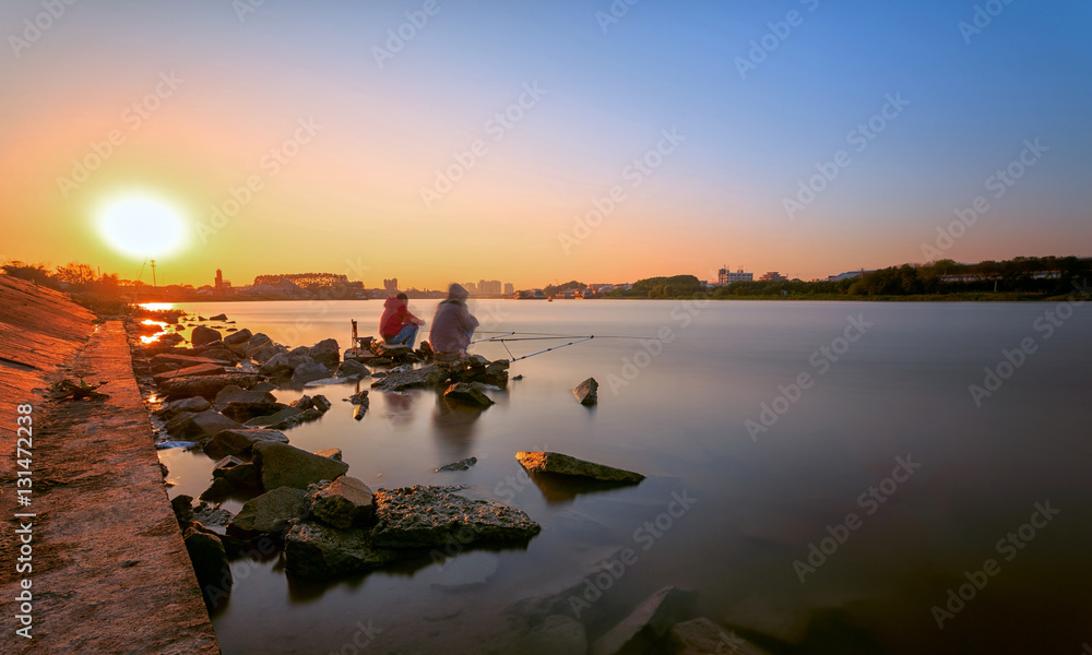 Two fishermen fishing at sunset moment