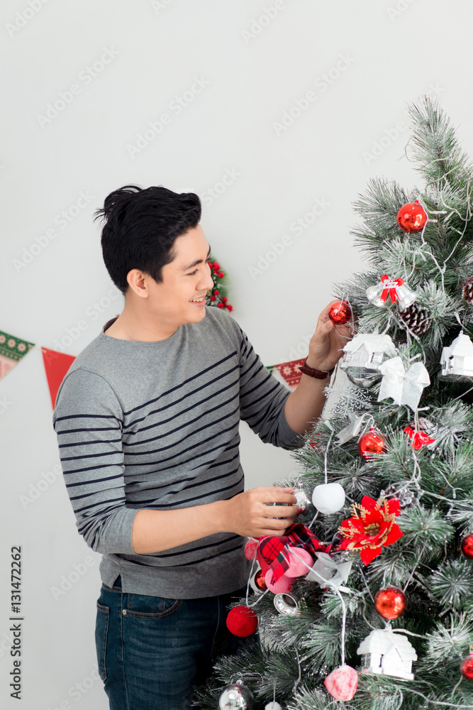 Christmas. Asian Handsome Man standing new Xmas tree at home cel