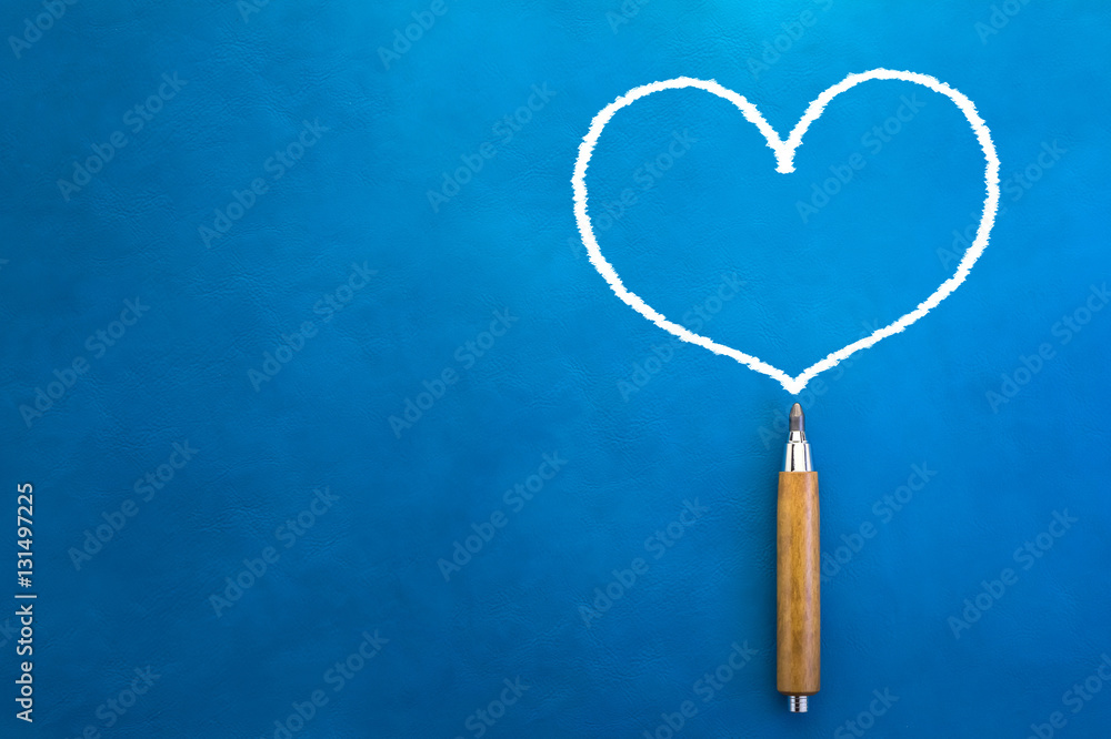 drawing of white heart shape with wooden pencil on blue backgrou