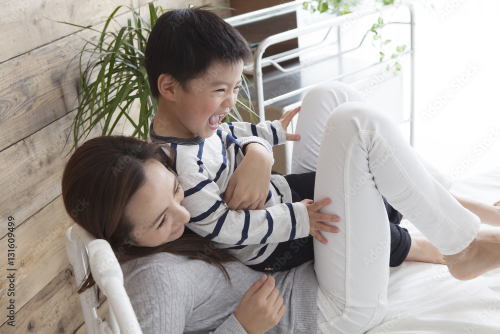 Mother and son are playing on the bed