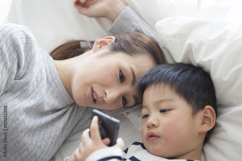 Mother and son are watching smartphone in bed