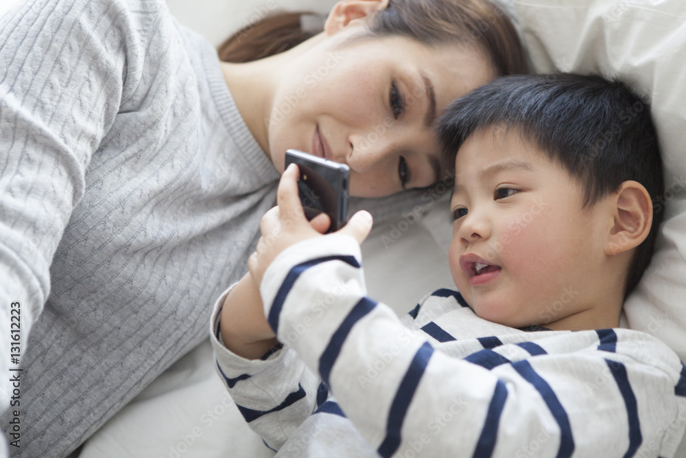 Mother and son are watching smartphone in bed