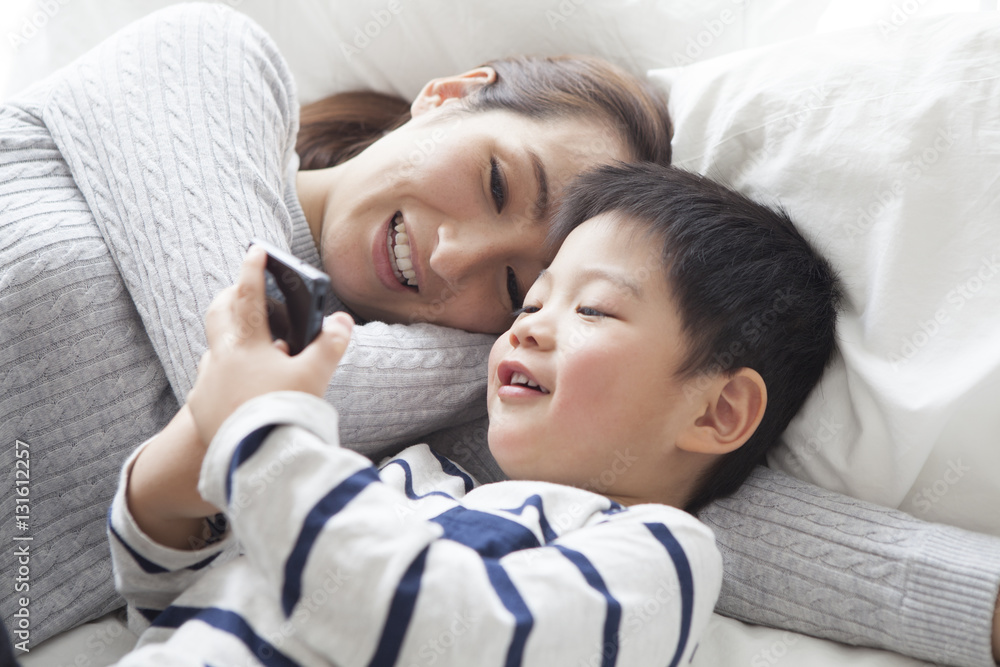 Mother and son are watching smartphone in bed