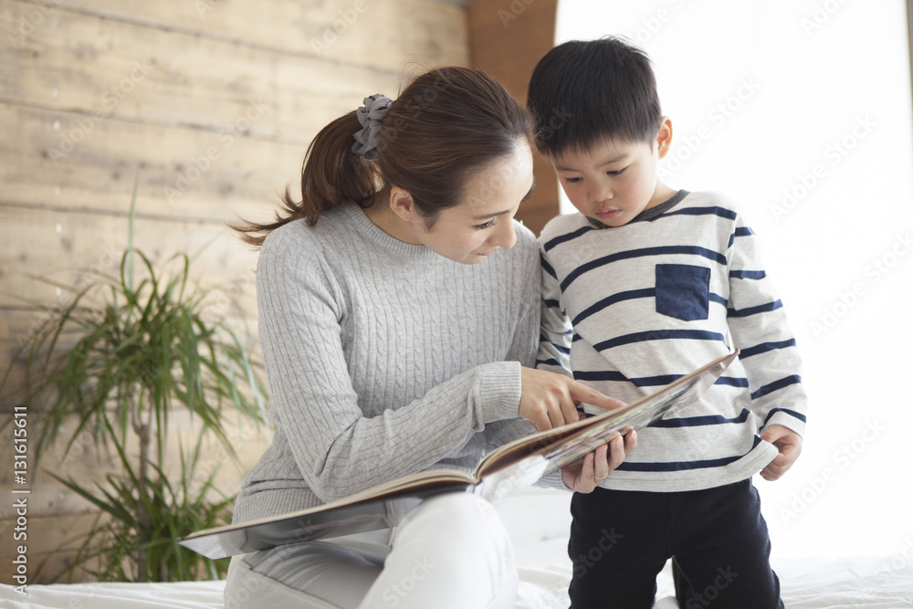 Mother and son are reading a picture book in the living room