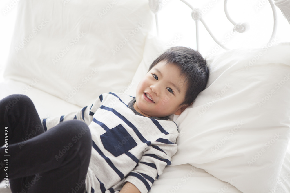 The boy is laughing on the bed