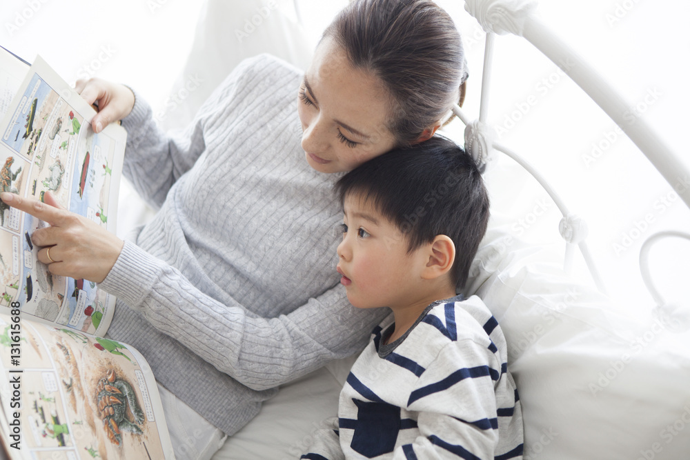 Mother and son are reading picture books in bed