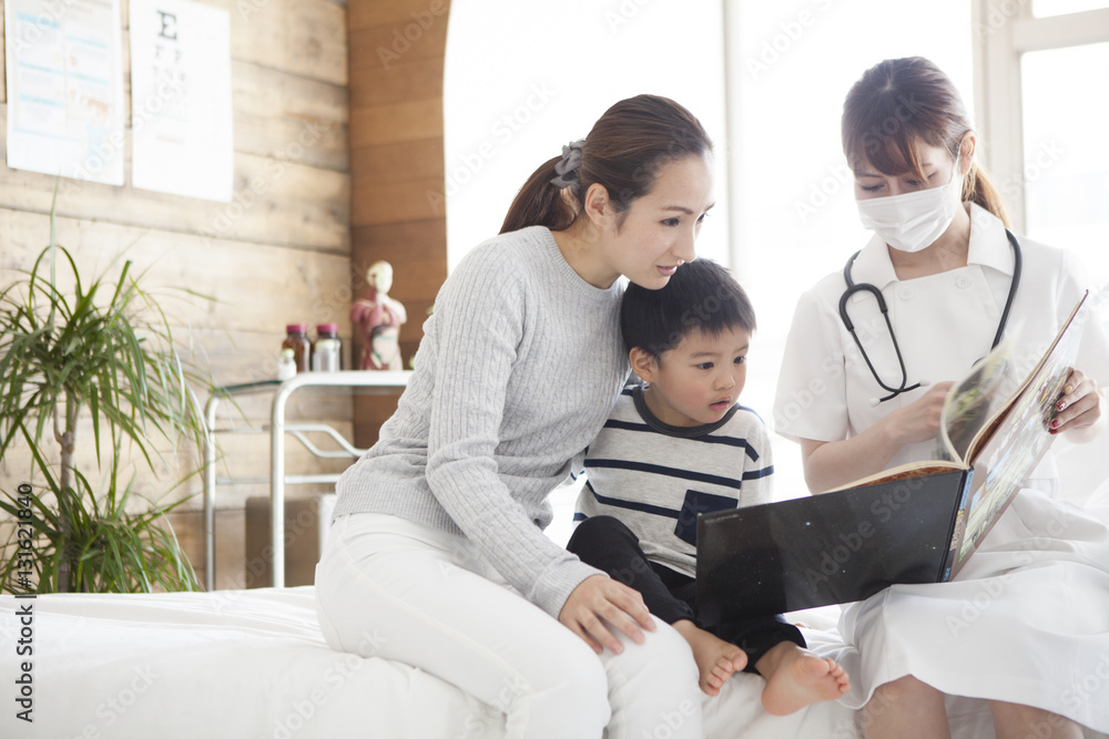 In pediatrics, a nurse is reading a picture book by a boy