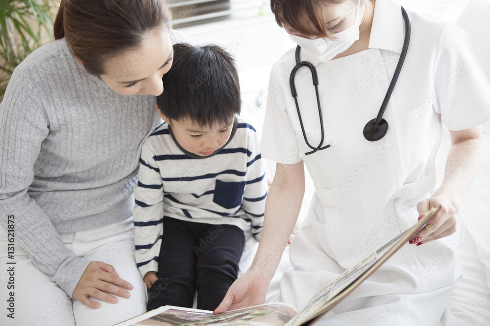 In pediatrics, a nurse is reading a picture book by a boy