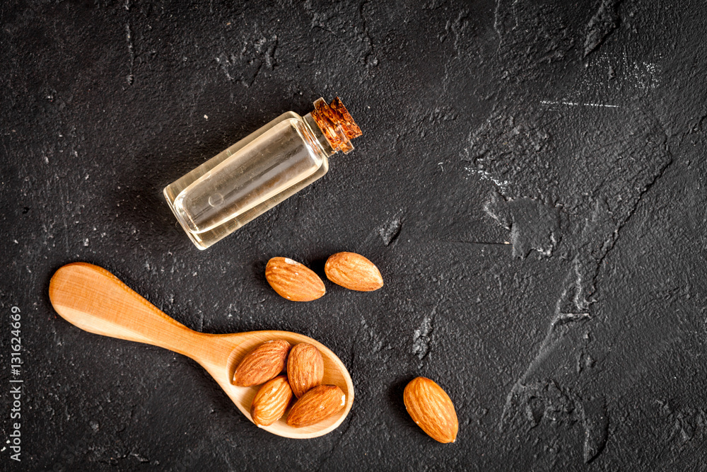 cosmetic almond oil in glass bottle on dark background