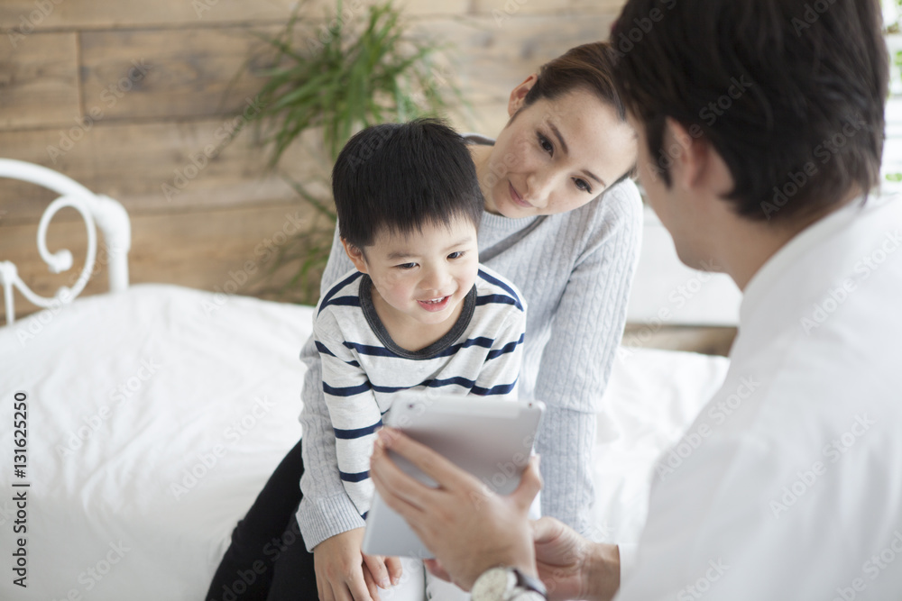 Pediatrician physician is showing tablet to mother and child