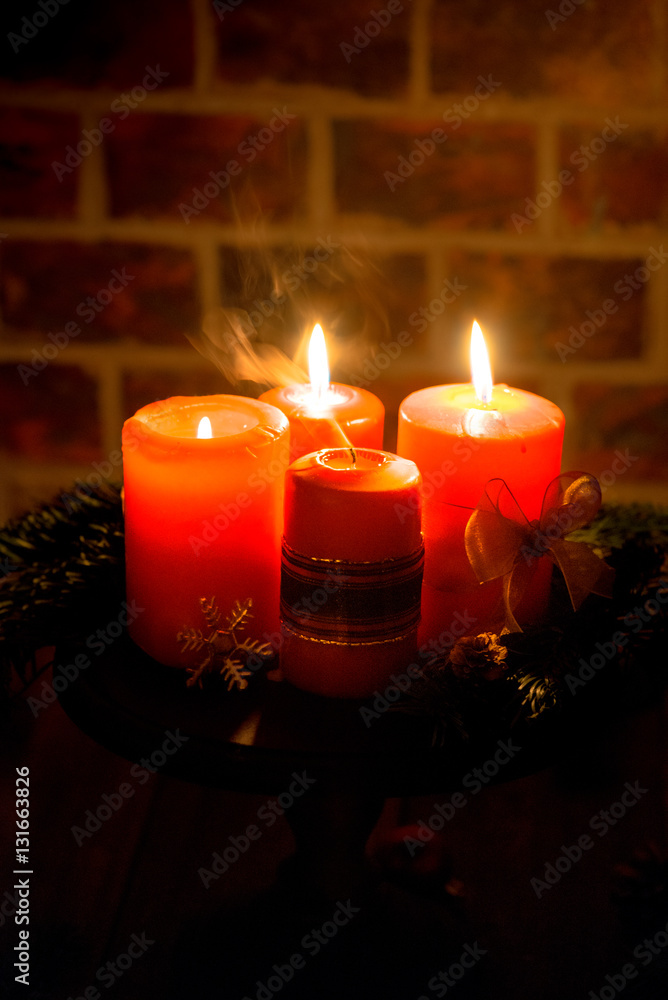 Four red candles with christmas decoration in atmospheric light. Moody. Authentic.