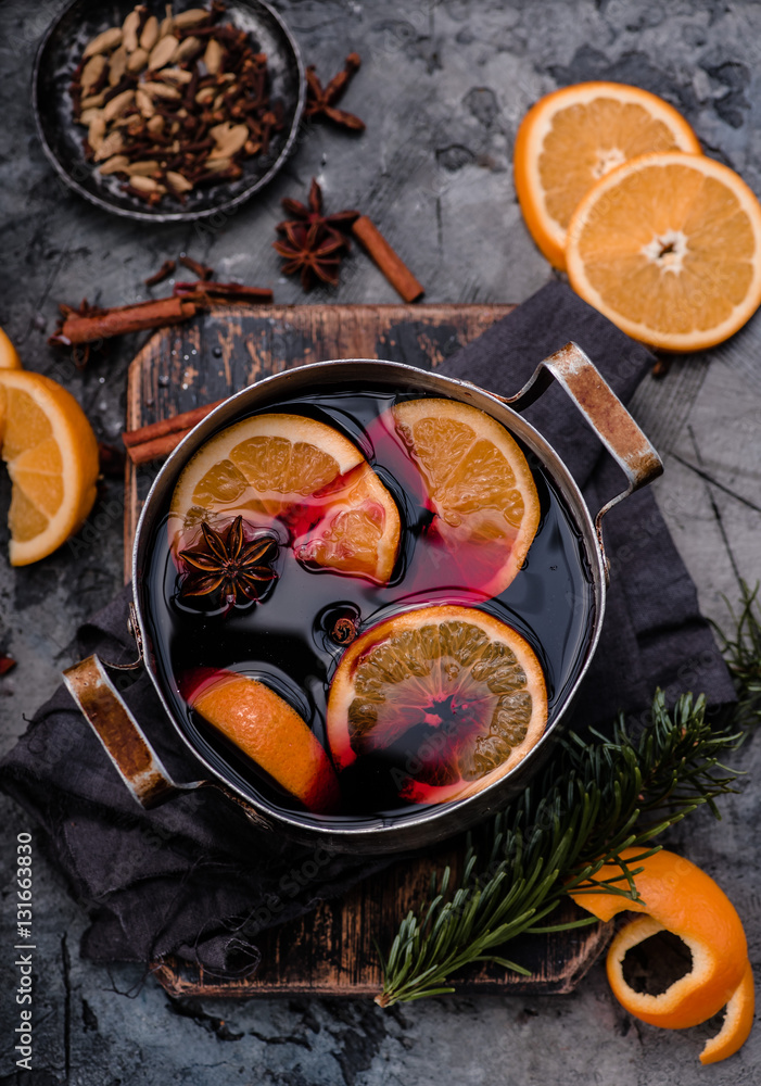 Mulled wine with orange and spices in aluminum vintage casserole on wooden board. Concrete backgroun