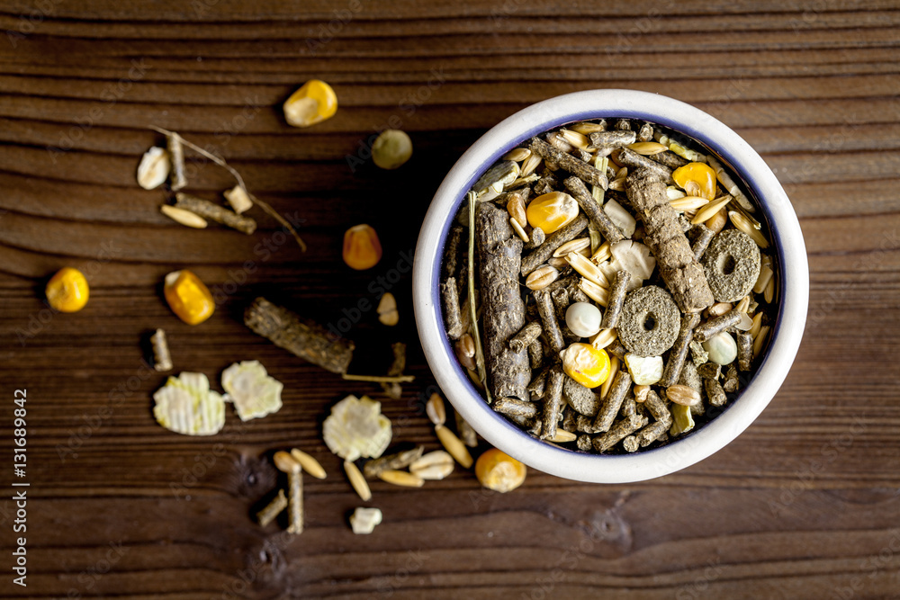 dry food for rodents in bowl wooden background top view