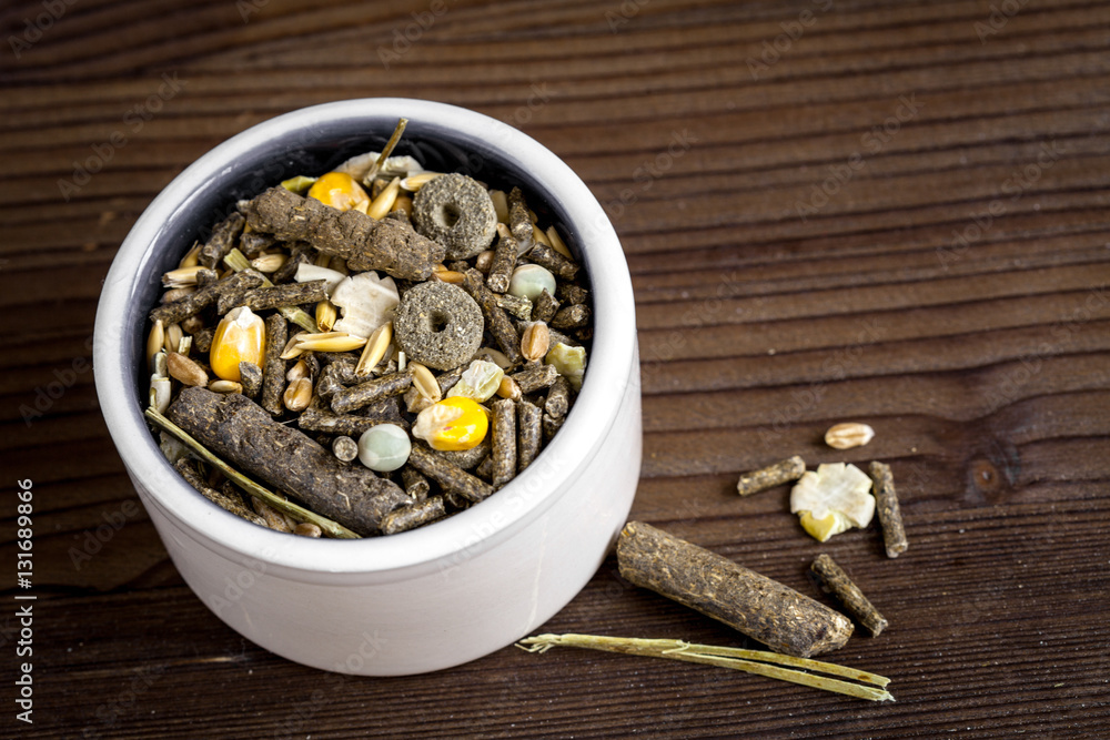 dry food for rodents in bowl wooden background