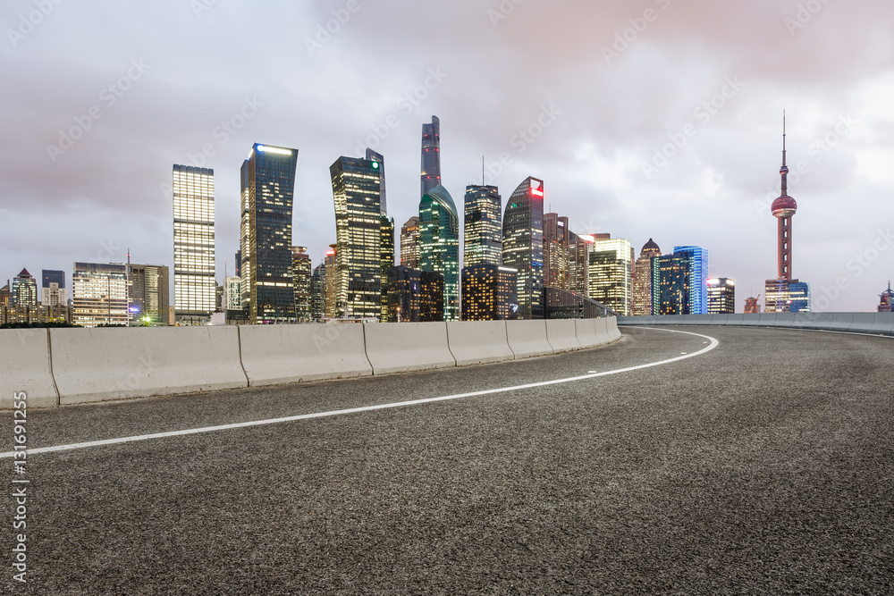 Asphalt road and modern cityscape at night in Shanghai