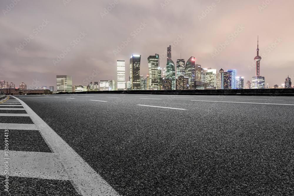 Asphalt road and modern cityscape at night in Shanghai