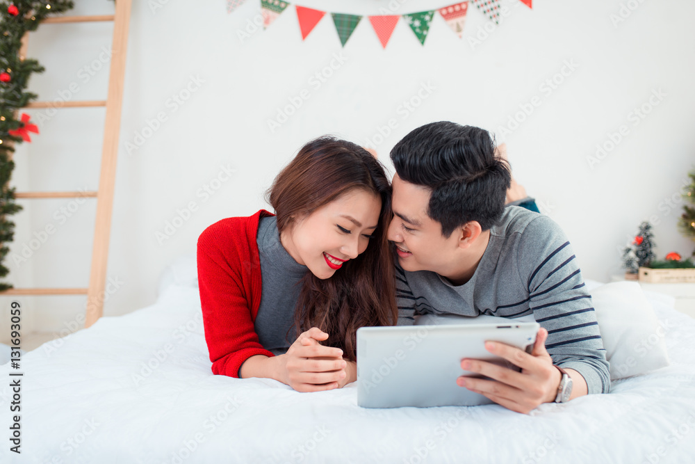 Christmas. Asian Couple using digital tablet at home celebrating