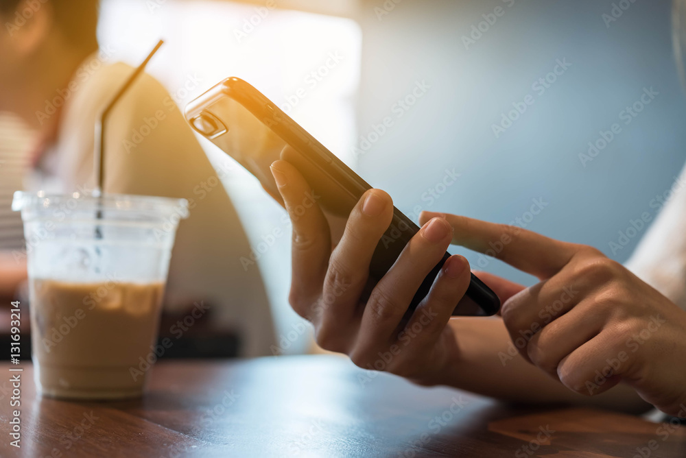 Closeup of hand using smartphone in coffee shop