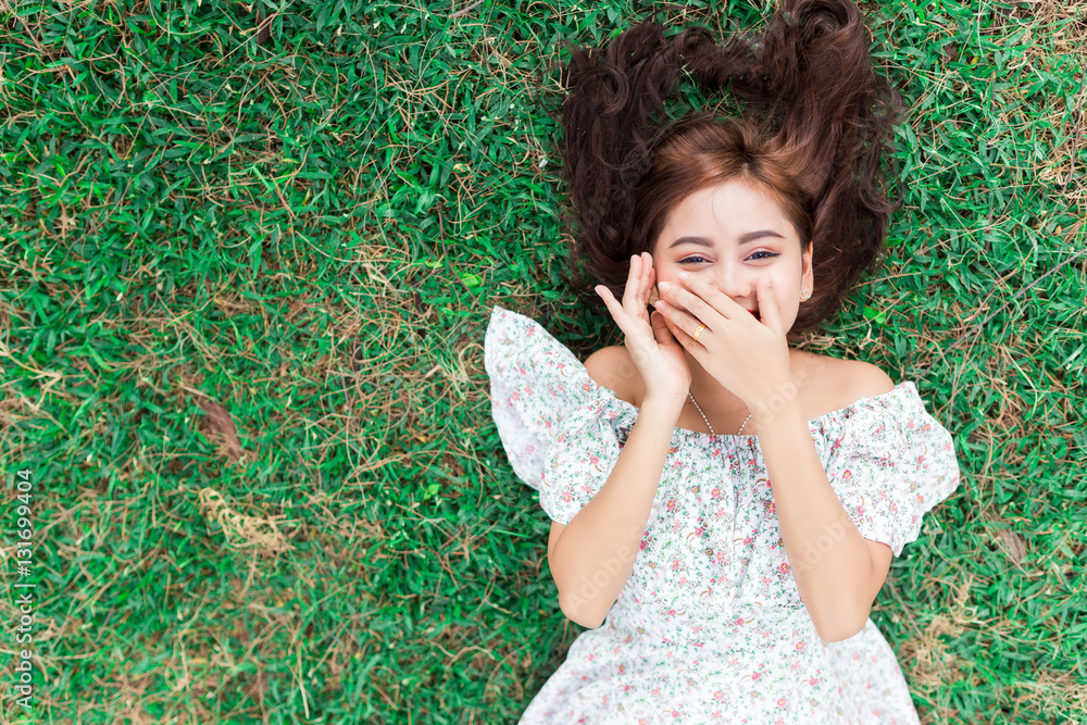 smiling happy girl lying down on a grass.