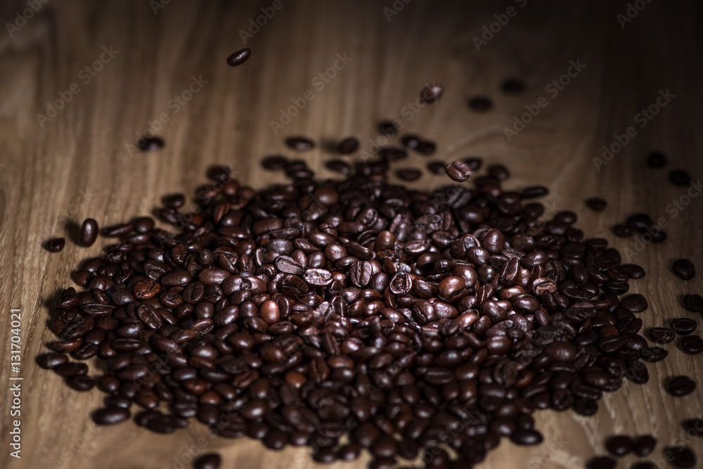 Dark coffee beans falling on the table