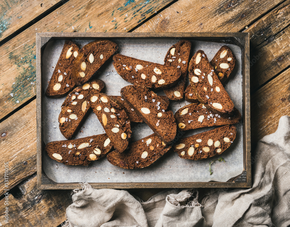 Dark chocolate and sea salt Biscotti with almonds in wooden tray over rustic wooden background, top 