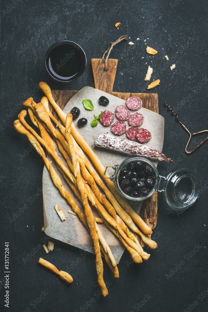 Wine and appetizers set. Italian Grissini bread sticks, dry cured pork meat sausage, black olives in