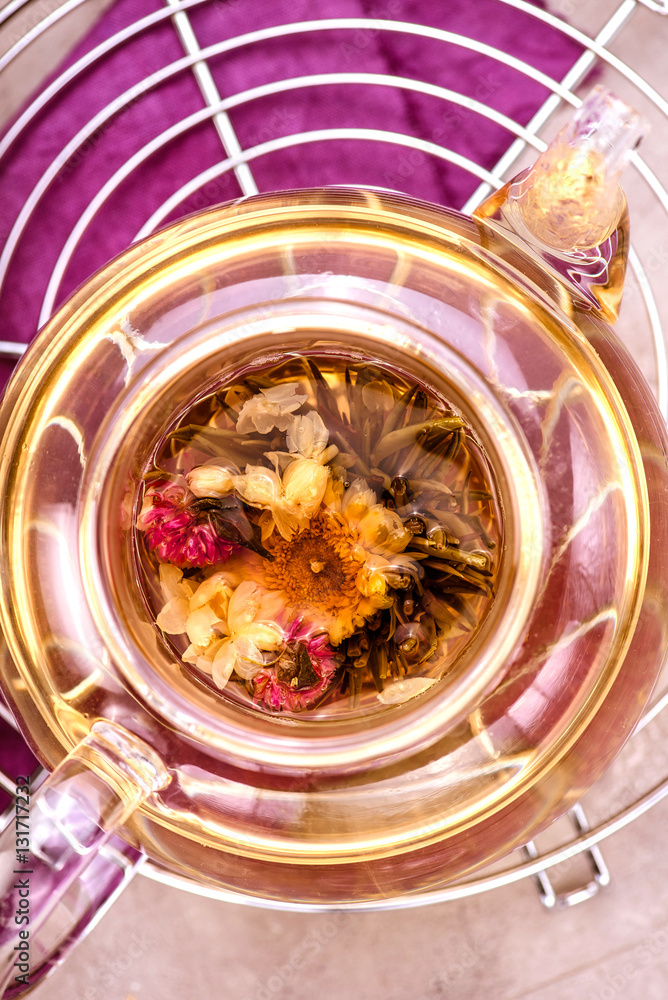 Glass teapot with tea on cooling rack. Concrete background. Top view.