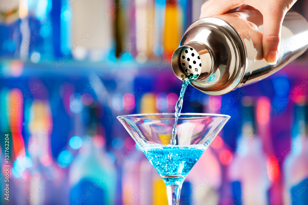 Barmans hand pouring liqueur to cocktail glass