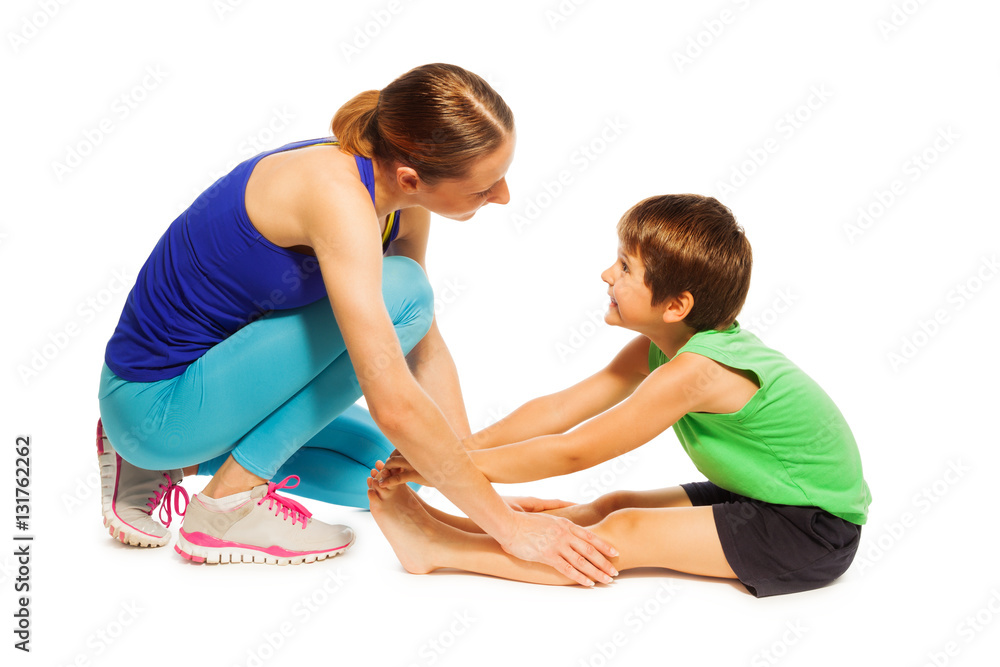 Young mother teaching son stretching leg muscles