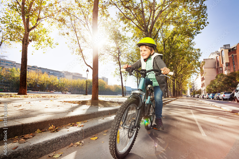 Happy boy cycling on bicycle path in autumn city