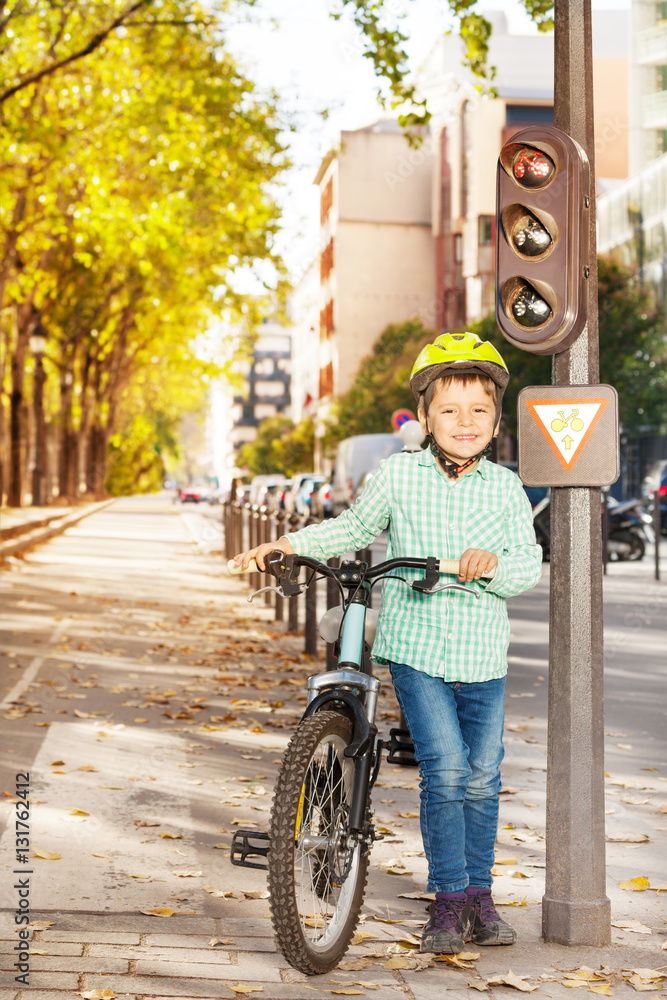 Boy waiting for green traffic light with his bike