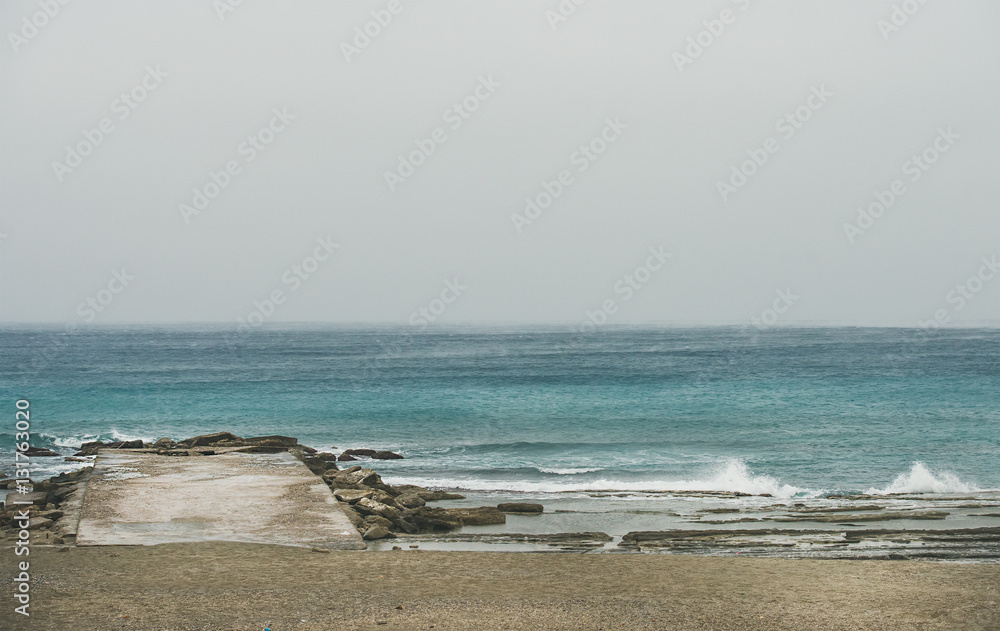 Empty sandy coast and pier at Mediterranean sea in winter day after storm in Alanya, Turkey