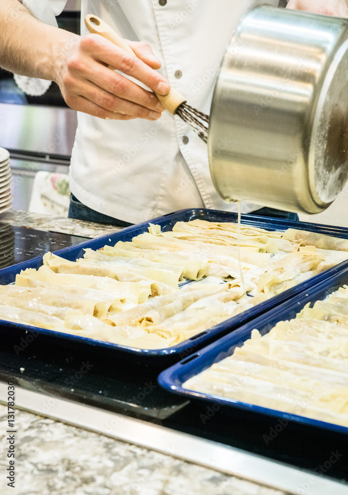 Cooking lasagna. The cook pours sauce. Italian Cuisine.