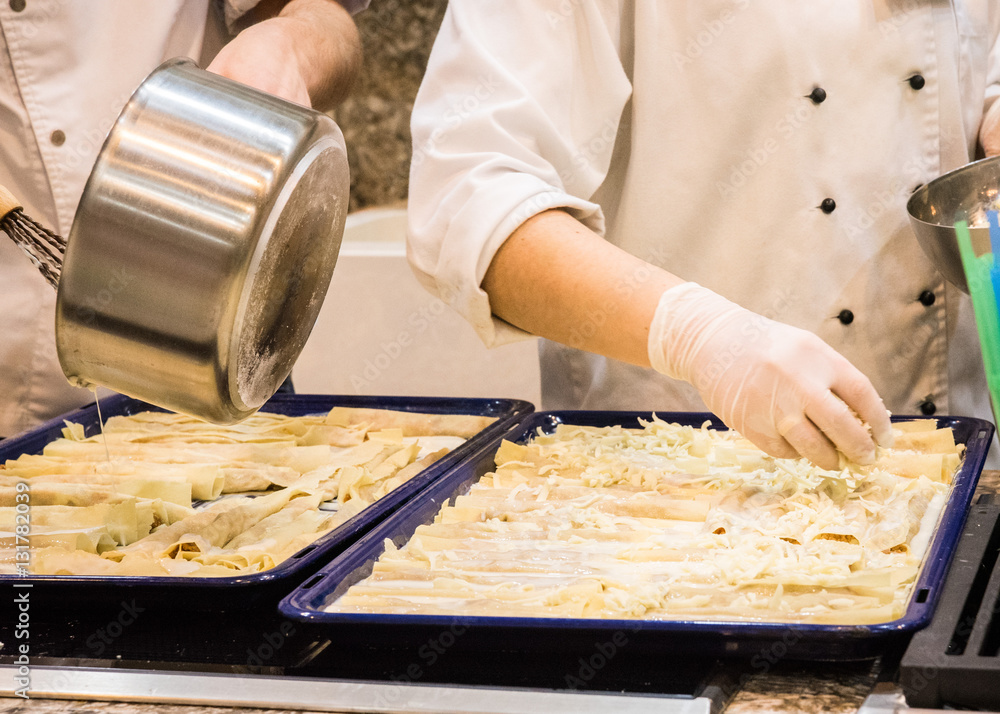 Cooking lasagna. The cook pours sauce. Italian Cuisine.